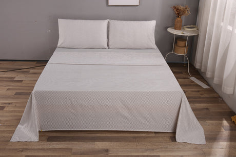 Gray textured bedspread on a bed in a room with wooden flooring and a small table.